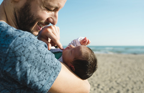 Vater mit seinem neugeborenen Mädchen am Strand, lizenzfreies Stockfoto