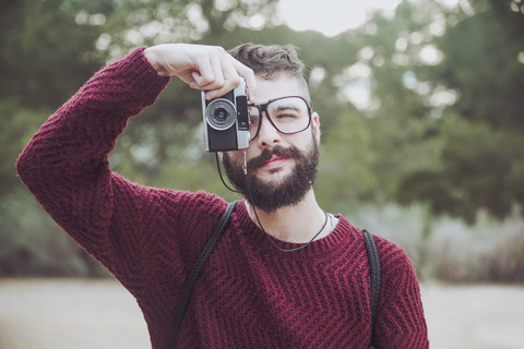 Portrait of bearded man with glasses taking photo with vintage camera stock photo