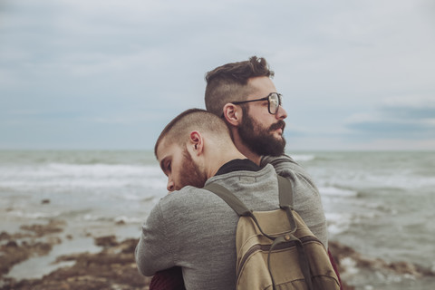 Young gay couple hugging on the beach stock photo