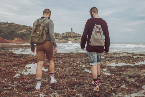 Spanien, Oropesa del Mar, zwei junge Männer gehen am steinigen Strand spazieren - RTBF00728