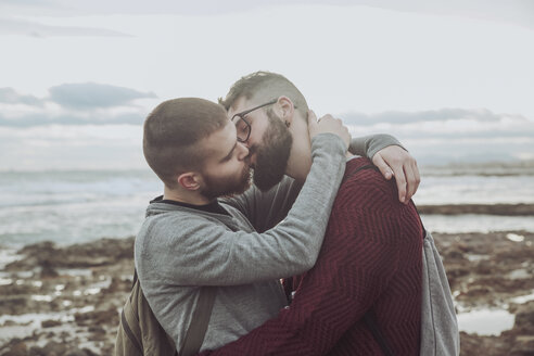 Junges schwules Paar umarmt und küsst sich vor dem Meer - RTBF00730