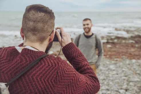 Mann, der seinen Freund vor dem Meer fotografiert - RTBF00733