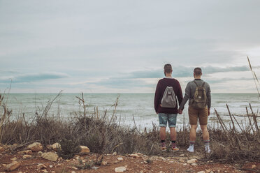 Back view of young gay couple looking at the sea - RTBF00739