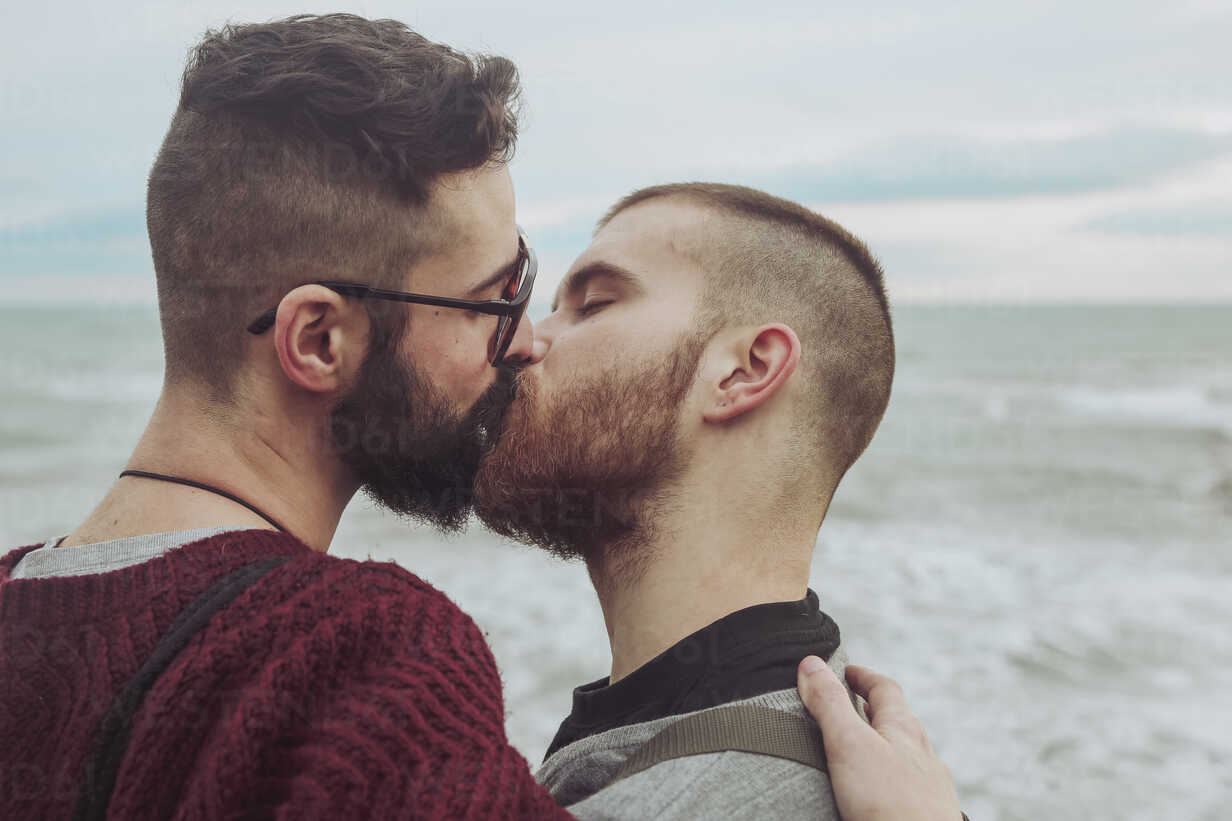 Gay couple kissing in front of the sea stock photo