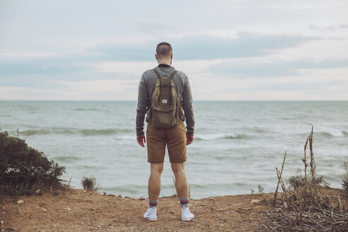 Rückenansicht eines jungen Mannes mit Rucksack und Blick aufs Meer - RTBF00744