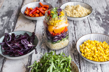 Glas Regenbogensalat mit Bulgur, Rucola und verschiedenen Gemüsesorten und Schalen mit Zutaten - SARF03241