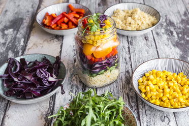 Glass of rainbow salad with bulgur, rocket and different vegetables and bowls with ingredients - SARF03241