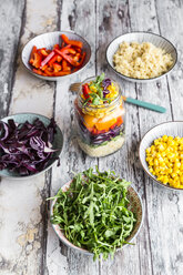 Glas Regenbogensalat mit Bulgur, Rucola und verschiedenen Gemüsesorten und Schalen mit Zutaten - SARF03242