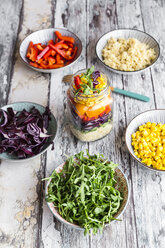 Glass of rainbow salad with bulgur, rocket and different vegetables and bowls with ingredients - SARF03242