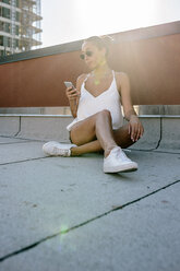 Relaxed woman sitting in armchair on rooftop in Brooklyn - GIOF02099