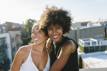 Female friends standing on rooftop, embracing - GIOF02111