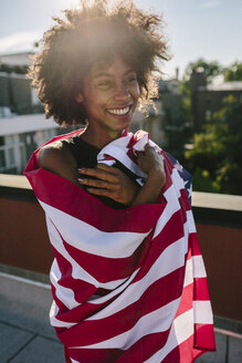 Junge Frau auf dem Dach stehend und mit US-amerikanischer Flagge bekleidet - GIOF02117