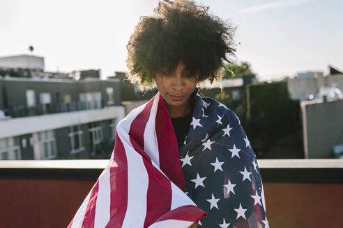 Junge Frau auf dem Dach stehend und mit US-amerikanischer Flagge bekleidet - GIOF02118