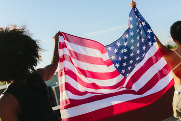 Freundinnen halten die US-amerikanische Flagge und stehen auf einem Dach - GIOF02121