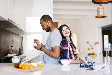 Junges Paar beim Frühstück in der Küche, Rücken an Rücken stehend - VABF01224