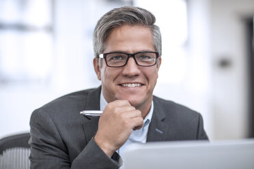 Geschäftsmann mit Brille im Büro sitzend, lächelnd - ZEF13067