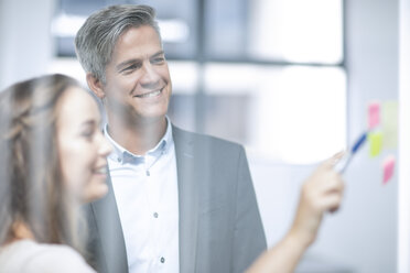 Business people standing by glass pane, brainstorming - ZEF13071