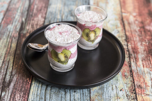 Zwei Gläser Chia-Pudding mit herzförmigen Kiwi-Scheiben auf dem Tablett - SARF03247