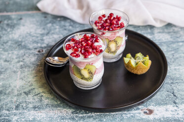 Zwei Gläser Chia-Pudding mit herzförmigen Kiwi-Scheiben und Granatapfelkernen auf dem Tablett - SARF03249