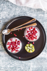Zwei Gläser Chia-Pudding mit Kiwi und Granatapfelkernen auf dem Tablett - SARF03250