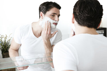 Young man standing in front of mirror, applying shaving foam - DIFF00005