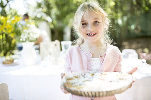 Portrait of smiling girl holding a pie outdoors - WESTF22771