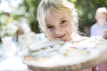 Porträt eines lächelnden Mädchens, das einen Kuchen im Freien hält - WESTF22774