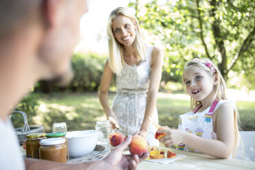 Happy family in garden preserving peaches - WESTF22778