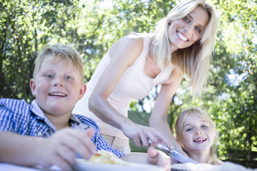 Smiling mother with children at garden table - WESTF22788