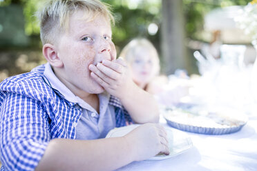 Porträt eines Jungen beim Essen am Gartentisch - WESTF22789