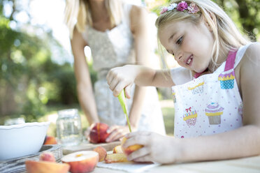 Girl preserving peaches at garden table - WESTF22800