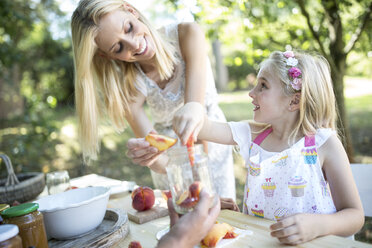 Smiling mother and daughter preserving peaches - WESTF22802