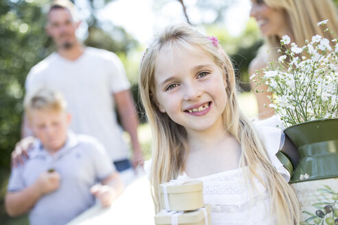 Porträt eines lächelnden Mädchens im Freien mit Familie im Hintergrund - WESTF22818