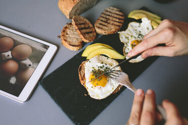 Frühstück mit Eiern, Avovados und getoastetem Brot auf einem Tisch mit digitalem Tablet - GIOF02147