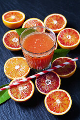 In Scheiben geschnittene Blutorangen und ein Glas Orangensaft auf einer Schiefertafel - CSF28005