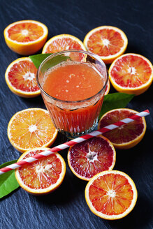 In Scheiben geschnittene Blutorangen und ein Glas Orangensaft auf einer Schiefertafel - CSF28005