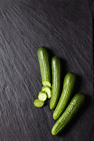 Geschnittene und ganze Mini-Gurken auf Schiefer, lizenzfreies Stockfoto