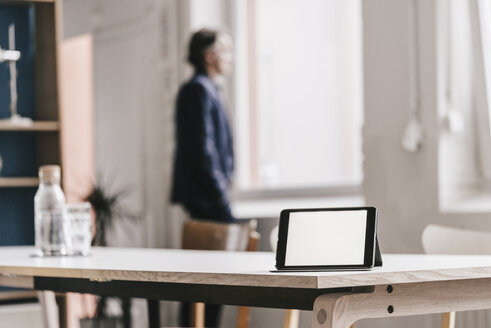 Tablet im Büro mit Geschäftsmann im Hintergrund - JOSF00687