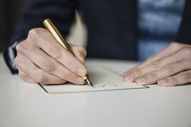 Hand of businessman writing with golden fountain pen, close-up - KNSF01133