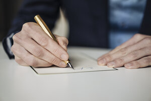 Hand eines Geschäftsmannes, der mit einem goldenen Füllfederhalter schreibt, Nahaufnahme - KNSF01133
