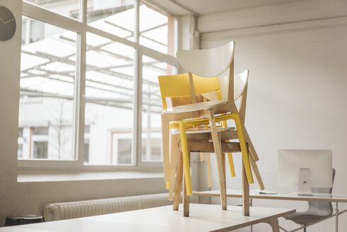 Stapel von Stühlen, die auf einem Besprechungstisch in einem Loft stehen - KNSF01143