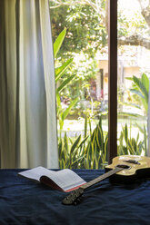 Guitar and book on bed - KNTF00667