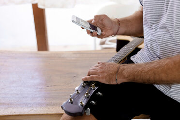 Nahaufnahme eines Mannes mit Gitarre und Mobiltelefon - KNTF00668