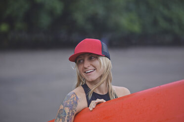 Smiling woman carrying surfboard on the beach - KNTF00673