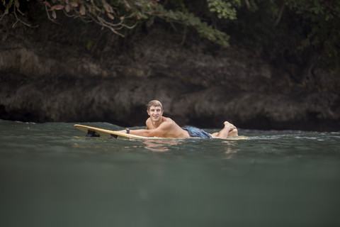 Indonesien, Java, Mann auf Surfbrett auf dem Meer liegend, lizenzfreies Stockfoto
