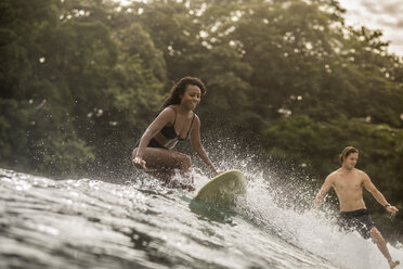 Indonesien, Java, glückliche Frau und Mann beim Surfen - KNTF00698