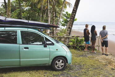 Indonesia, Java, friends standing at the coast next to car with surfboards - KNTF00726