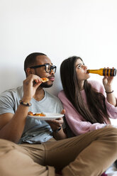 Young couple at home eating pizza and drinking beer - VABF01251