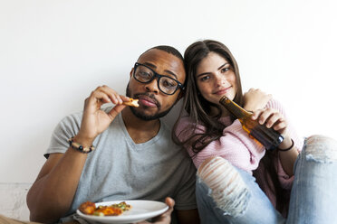 Young couple at home eating pizza and drinking beer - VABF01252