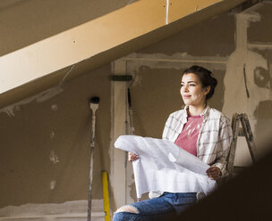 Junge Frau bei der Renovierung ihres neuen Hauses, mit Bauplan - UUF10074